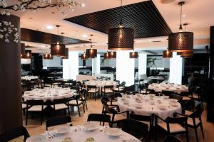 un restaurante con mesas y sillas blancas y lámparas de araña en Hotel Benetusser en Benetúser