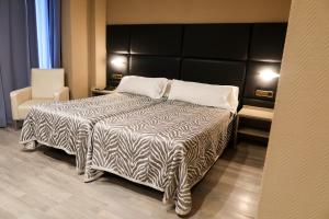 a bedroom with a bed with a black and white comforter at Hotel Benetusser in Benetúser