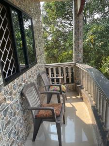 2 sillas sentadas en un porche con ventanas en NO NAME GUESTHOUSE, en Arambol