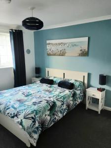 una camera da letto con un letto con una parete blu di Inner Harbour Cottage a Portreath