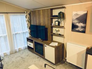 ein Wohnzimmer mit einem Flachbild-TV auf einem Schreibtisch in der Unterkunft Silver Birch Lodge Aviemore in Aviemore