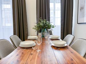 a wooden table with chairs and plates and wine glasses at Best Price & Location - Historic Square Residency in Prague