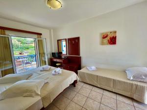 two beds in a room with a balcony at Venardos Hotel in Agia Pelagia