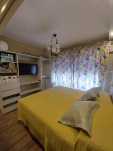 a bedroom with a yellow bed and a television at EDIFICIO ALVARADO in Salta