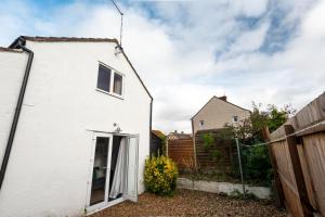 ein weißes Haus mit einem Tor und einem Zaun in der Unterkunft Well Coach House by Cliftonvalley Apartments in Bristol