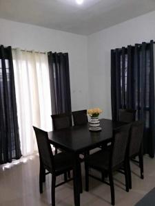 une salle à manger avec une table et des chaises noires dans l'établissement Vacation home in Lancaster new city Cavite Philippines, à General Trias