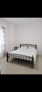 Cama en habitación blanca con marco de cama en Vacation home in Lancaster new city Cavite Philippines, en General Trias
