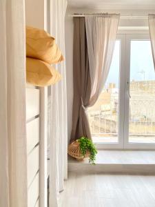 1 dormitorio con 1 cama con cortinas y ventana en Charming Duplex Penthouse Near Valletta., 