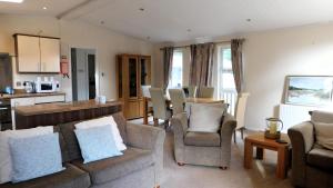 sala de estar con sofá y sillas y cocina en The Lodge, Alder Country Park, en North Walsham