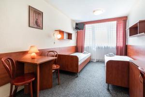 a room with two beds and a table and chairs at Hotel Alf in Krakow