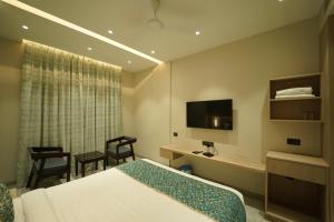 een hotelkamer met een bed, een bureau en een televisie bij HOTEL LAKSH in Raipur