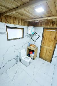 a bathroom with a toilet and a wooden door at Himalayan Cedar Nest in Sainj