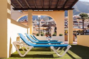 a group of blue lounge chairs on a patio at Ramada Costa Adeje Apartment in Adeje