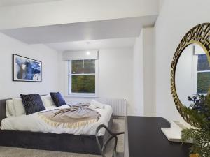 a white bedroom with a bed and a mirror at The Grove King bed Wi-Fi EV Charger in Cheltenham