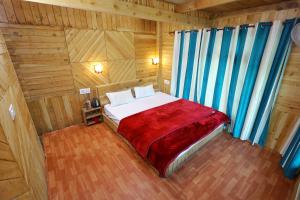 ein Schlafzimmer mit einem Bett in einem Holzzimmer in der Unterkunft Himalayan Cedar Nest in Sainj