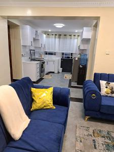 uma sala de estar com um sofá azul e uma cozinha em Elysian Homes em Nakuru