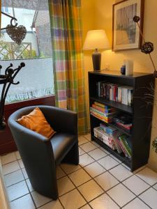 una stanza con una sedia e una libreria con libri di Ferienwohnung Helfenstein a Idar-Oberstein