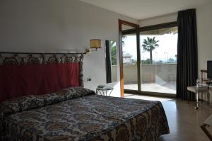 Habitación de hotel con cama y puerta corredera de cristal en Hotel Villa Undulna - Terme della Versilia en Cinquale