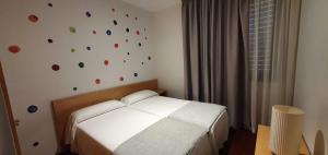 Un dormitorio con una cama blanca y una pared con puntos coloridos en Anchieta 60, en La Laguna