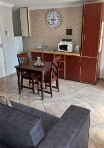 kuchnia ze stołem i krzesłami oraz zegarem na ścianie w obiekcie Jakkalsdraai Guest House w mieście Potchefstroom