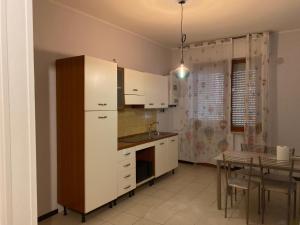 a kitchen with white cabinets and a table and a dining room at Casa Barnabei 26 in Teramo