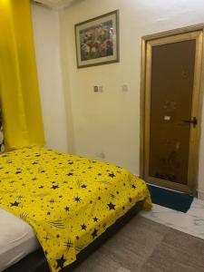 1 dormitorio con 1 cama con manta amarilla y flores en Appartement a hedzranawoe, en Lomé