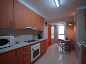 a kitchen with wooden cabinets and a table with a microwave at Lets Holidays Tossa de Mar Ancora in Tossa de Mar