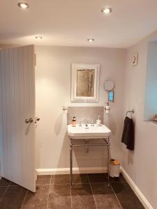 ein Badezimmer mit einem weißen Waschbecken und einem Spiegel in der Unterkunft Brabands Cottage Rye in Iden