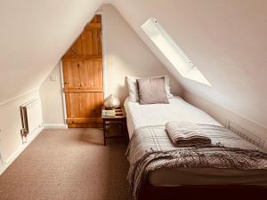 a attic bedroom with a bed and a window at Brabands Cottage Rye in Iden