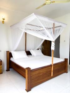 a bed with a canopy in a room at Kijiji Villas Nungwi in Banda Kuu