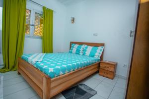 a small bed in a room with green curtains at Appartement Meublé Bonamoussadi Douala in Deido