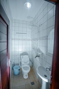 a white bathroom with a toilet and a sink at Appartement Meublé Bonamoussadi Douala in Deido