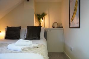 1 dormitorio con 1 cama con almohadas blancas y negras en Woodstock Oxford Street- Entire Cosy Apartment- 5 mins to Blenheim Palace en Woodstock