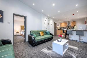 ein Wohnzimmer mit einem grünen Sofa und einer Küche in der Unterkunft *F4GH for your most relaxed & Cosy stay + Free Parking + Free Fast WiFi * in Bramley