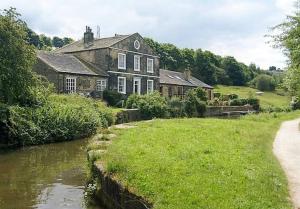 an old house next to a river in a field at *F4GH for your most relaxed & Cosy stay + Free Parking + Free Fast WiFi * in Bramley