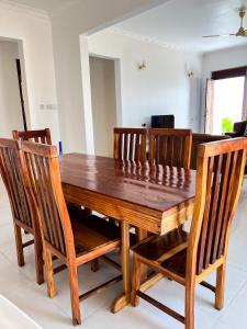 a wooden dining room table with four wooden chairs at Kijiji Villas Nungwi in Banda Kuu
