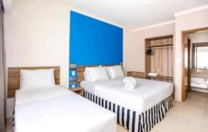 two beds in a hotel room with a blue wall at Ondas Praia Resort in Porto Seguro