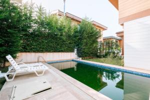 a swimming pool with a chair next to a house at Chic Villa w Pool Garden Fireplace in Sile in Istanbul