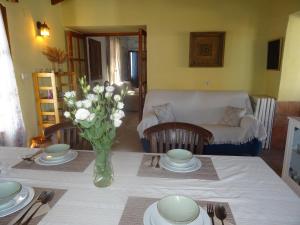 een woonkamer met een tafel met een vaas met bloemen bij La Casa del Campo de La Matanza 