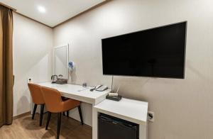 Habitación con escritorio y TV de pantalla plana en la pared. en Rex Hotel, en Seogwipo