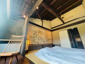 een slaapkamer met een bed en een stoel erin bij 京都　水凪庵　Kyoto Mizunagian in Giommachi