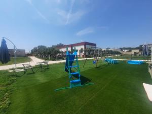 a playground with a blue slide on a green lawn at Il Casale di Punta Prosciutto in Punta Prosciutto