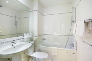 a white bathroom with a sink and a toilet and a tub at Lautrec Opera in Paris