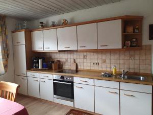 uma cozinha com armários brancos e um lavatório em Urlaubsruhe em Freudenberg