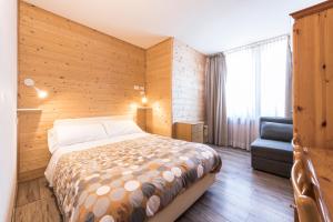 1 dormitorio con 1 cama y 1 silla en Hotel Vescovi en Asiago