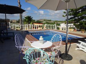 een tafel en stoelen met een parasol en een zwembad bij La Casa del Campo de La Matanza 