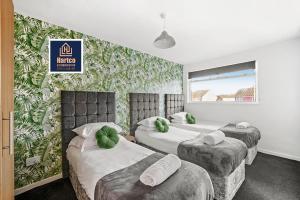 a hotel room with three beds with green leaves on the wall at Birmingham NEC Work stays in Birmingham