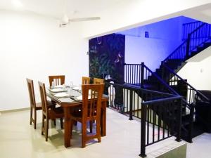 een eetkamer met een tafel en stoelen en een trap bij Villa of Green in Galle