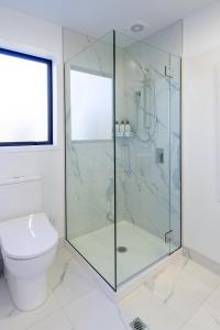 a bathroom with a glass shower with a toilet at Serenity Getaway in Christchurch