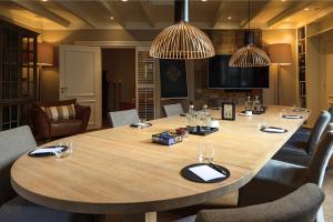 een grote houten tafel in een kamer met stoelen bij Villa de Duinen - Adults Only in Noordwijk aan Zee